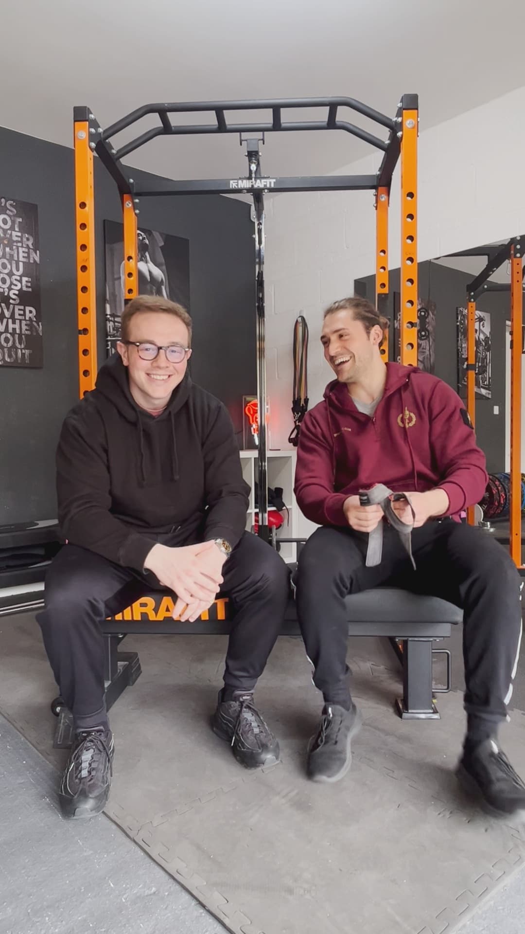 Harry and Tommy sitting together at the rack after a session at West 4 Gym, laughing.